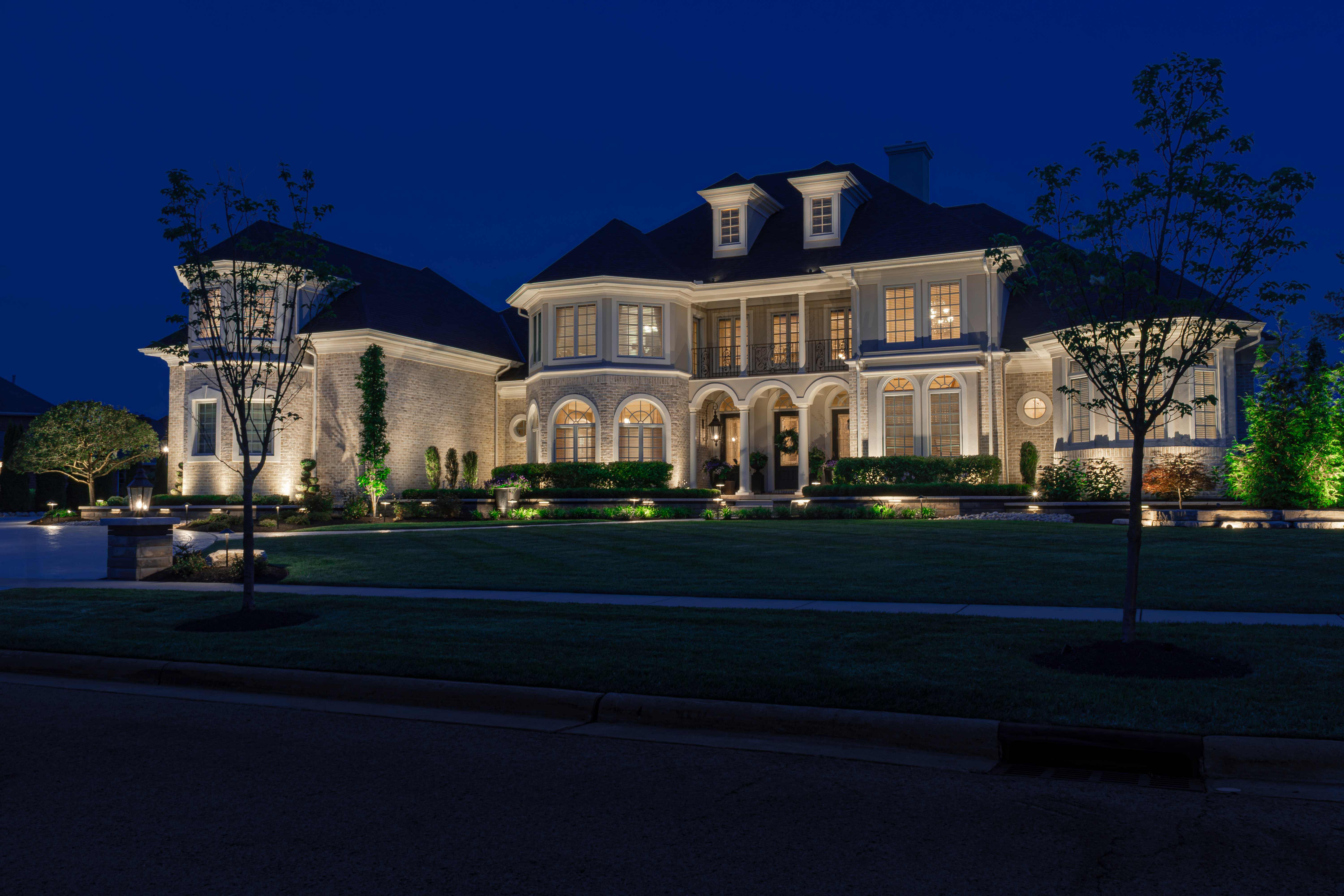 Luxury estate home with professional architectural and landscape lighting at twilight, showcasing premium outdoor illumination design