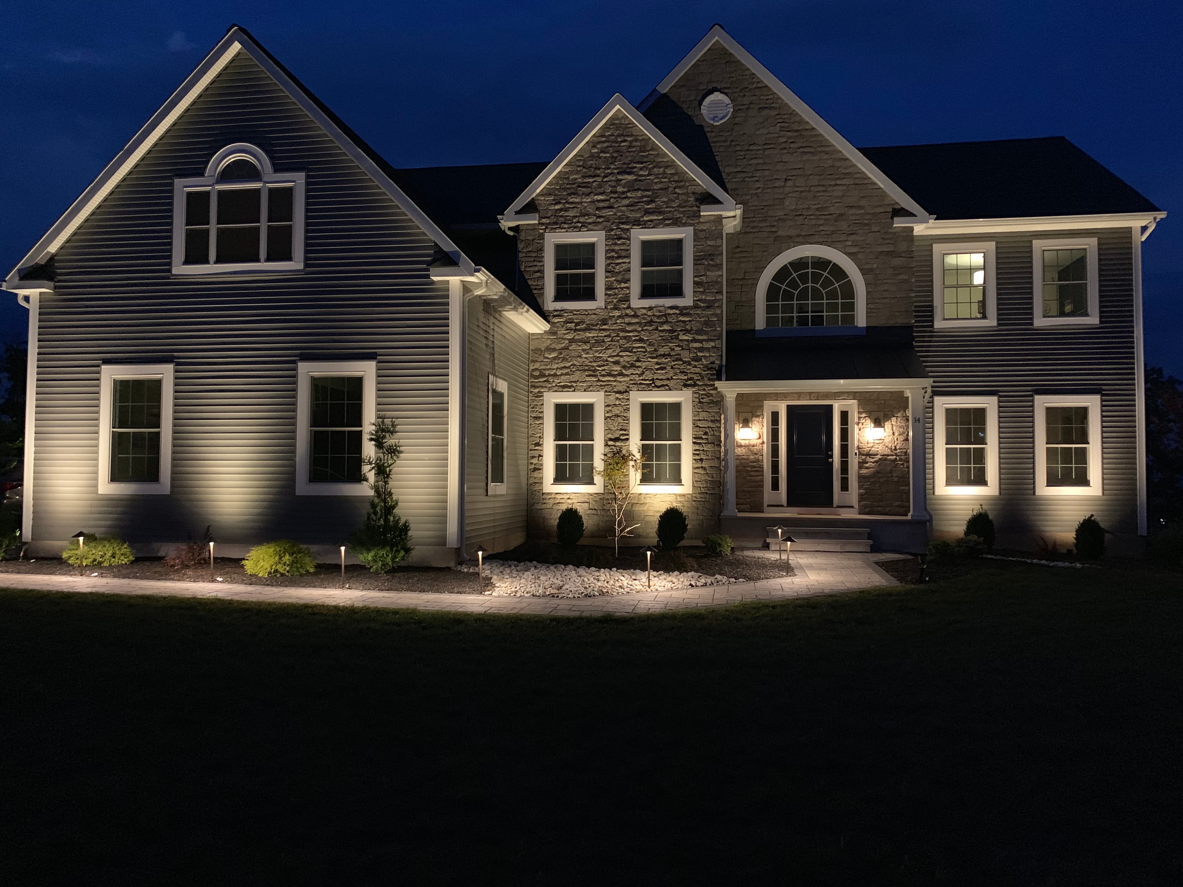 Large two-story home at night with architectural uplighting, pathway lights, and comprehensive exterior lighting in Auburn Alabama
