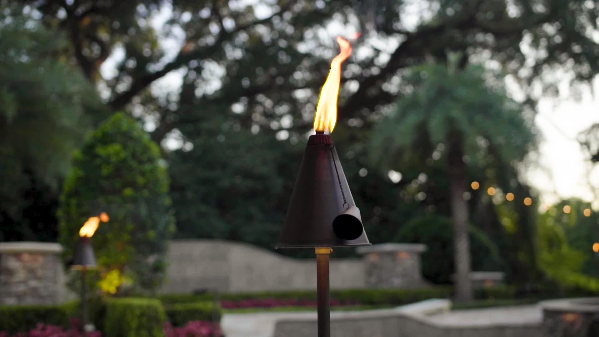 Artistic shot of tiki torch-style path light with flame at dusk showing ambient outdoor lighting for events in Auburn Alabama