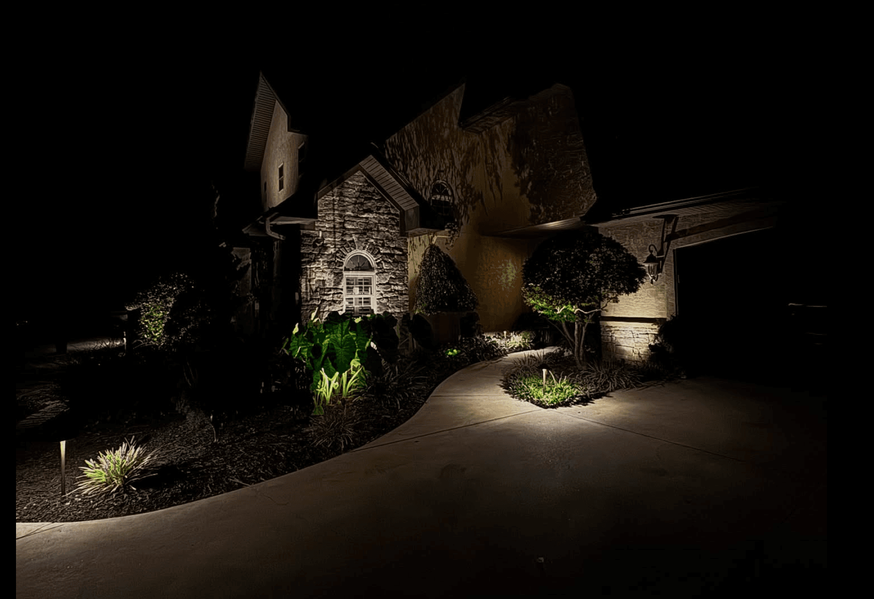 Luxury stone home with dramatic pathway lighting