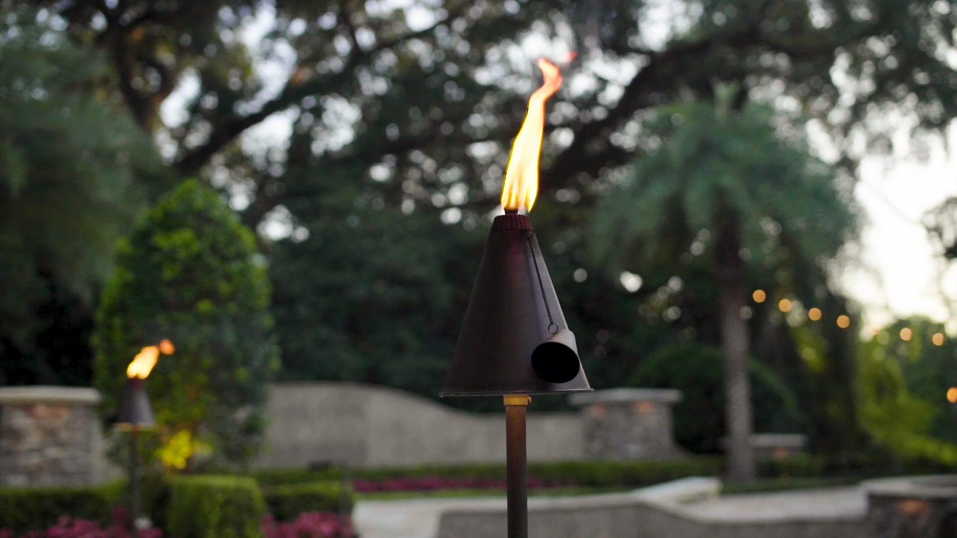 Tiki Torch Event Lighting Artistic shot of tiki torch-style path light with flame at dusk showing ambient outdoor lighting for events in Auburn Alabama